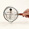 360° Rotating Glass Teapot on a warm ivory studio background