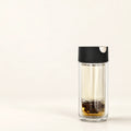Double-Wall Glass Tea Infuser Bottle on a warm ivory studio background