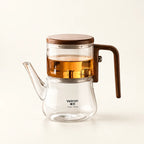Glass Infuser Teapot with Wood Handle on a warm ivory studio background